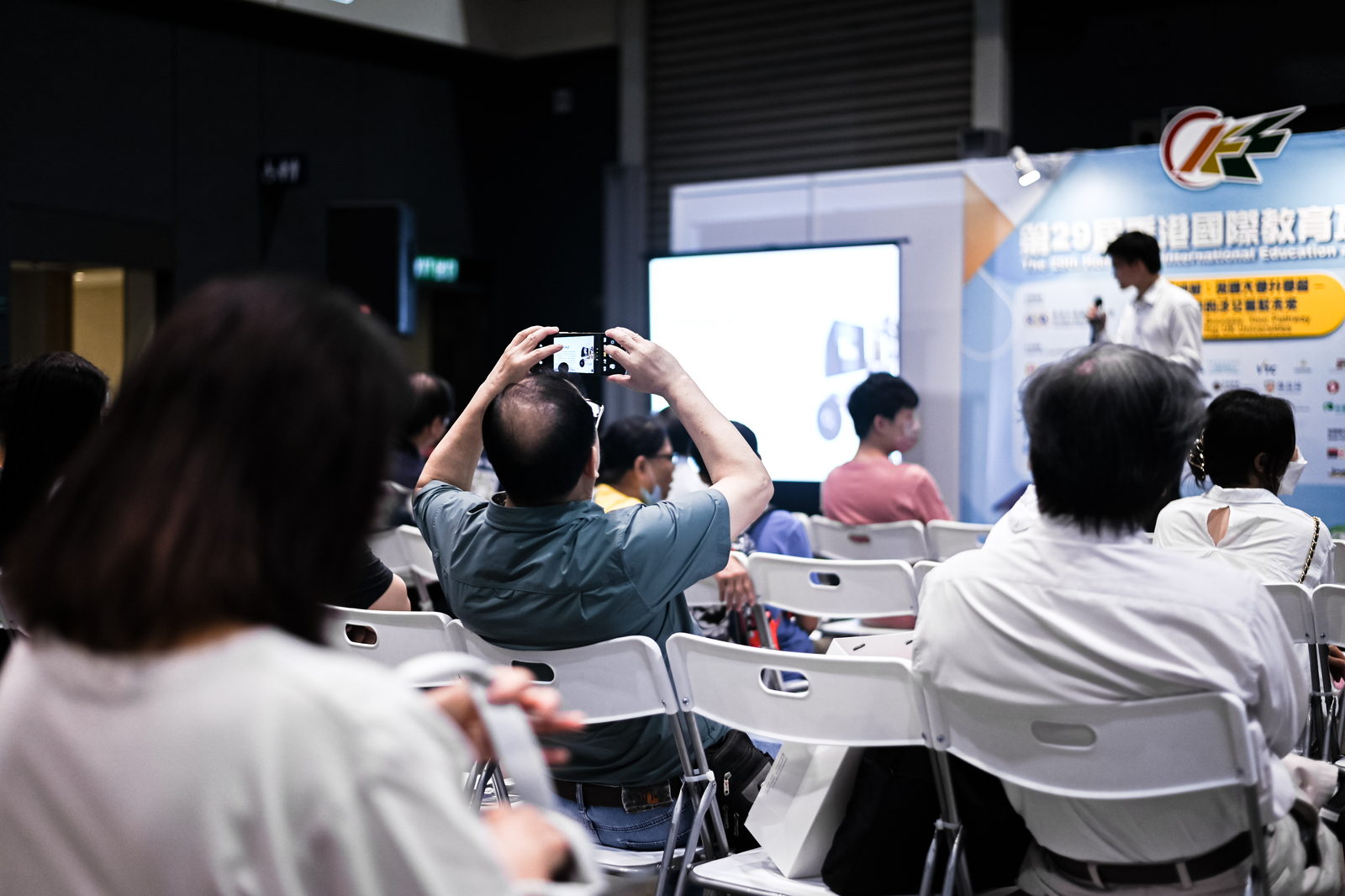 Parents and students seated at the talk, one of them photographing the slide.
